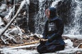 Man practicing kendo with bamboo sword on waterfall background. Place for text or advertising