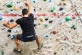 Man practicing rock climbing on artificial wall indoors. Active lifestyle and bouldering concept Royalty Free Stock Photo