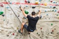 Man practicing rock climbing on artificial wall indoors. Active lifestyle and bouldering concept Royalty Free Stock Photo