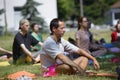 Man practicing yoga at the city park, group of people meditating on a background