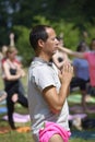 Man practicing yoga at the city park, group of people meditating on a background