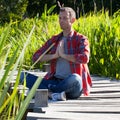 Man practising yoga sitting on wood bridge with reed around Royalty Free Stock Photo