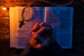 Man praying on the Bible by candlelight selective focus