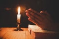 Man praying on the holy Bible in the light candles selective focus Royalty Free Stock Photo