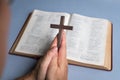 Man praying holding cross crucifx with open bible at the background Royalty Free Stock Photo