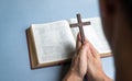 Man praying holding cross crucifx with open bible at the background Royalty Free Stock Photo