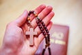 Man is praying: Rosary in the hands, holy bible in the background