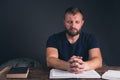 A man prays with folded hands. An open Holy Bible on the table. A young man with a beard. Royalty Free Stock Photo