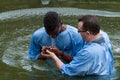 Yardenit, Israel - 29 Decembre 2012: a man prays after his baptism in the Jordan River. The priest holds his hands Royalty Free Stock Photo