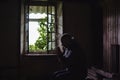 A man prays in an old crumbling house. Abandoned house with an open window from the inside. Hope, despair concept