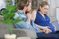 man and pregnant woman lying on sofa with pain