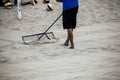 The man prepares a beach volleyball court using the rake