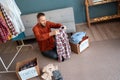 Man prepares clothes for donation box sitting on the floor at home. Donation concept Royalty Free Stock Photo