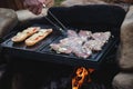 Man prepares a juicy pork neck with basil and barbecue spices and a baguette with tomato cheese and ham on a hot granite slab.