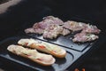 Man prepares a juicy pork neck with basil and barbecue spices and a baguette with tomato cheese and ham on a hot granite slab.