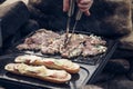 Man prepares a juicy pork neck with basil and barbecue spices and a baguette with tomato cheese and ham on a hot granite slab.