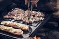 Man prepares a juicy pork neck with basil and barbecue spices and a baguette with tomato cheese and ham on a hot granite slab.