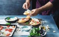 Man is preparing bruschetta with baked tomato, cheese and garlic