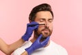 Man preparing for cosmetic surgery, pink background. Doctor drawing markings on his face, closeup Royalty Free Stock Photo