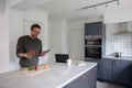 Man preparing food in kitchen and working from home Royalty Free Stock Photo