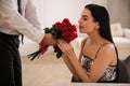 Man presenting roses to his beloved woman indoors. Valentine`s day celebration
