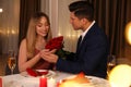 Man presenting roses to his beloved woman in restaurant at romantic dinner