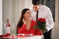 Man presenting roses to his beloved woman in restaurant. Romantic Valentine`s day dinner