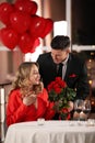 Man presenting roses to his beloved woman in restaurant at Valentine`s day dinner