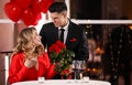 Man presenting roses to his beloved woman in restaurant at Valentine`s day dinner