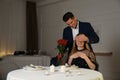 Man presenting roses to his beloved woman in restaurant at romantic dinner