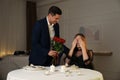 Man presenting roses to his beloved woman at romantic dinner