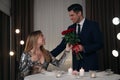 Man presenting roses to his beloved woman in restaurant at romantic dinner