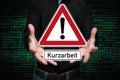 Man presents traffic sign in hands with the inscription Kurzarbeit German word for short Time work