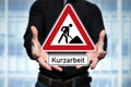 Man presents traffic sign in hands with the inscription Kurzarbeit German word for short Time work