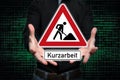 Man presents traffic sign in hands with the inscription Kurzarbeit German word for short Time work