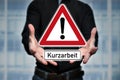 Man presents traffic sign in hands with the inscription Kurzarbeit German word for short Time work