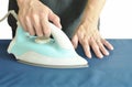 Man pressing blue automatic electric iron to shirt on ironing board Royalty Free Stock Photo