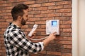 Man pressing button on intercom panel indoors