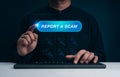 Man pressing Report a Scam button on virtual interface while using computer. Online fraud prevention, internet scam alert, Royalty Free Stock Photo