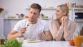 Man pretending to eat with pleasure wifes unappetizing meal, couple relationship