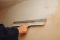 Man is priming a surface with a palett knife. Maintenance repair works renovation in the flat. Restoration indoors. Concrete