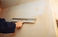Man is priming a surface with a palett knife. Maintenance repair works renovation in the flat. Restoration indoors. Concrete