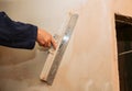 Man is priming a surface with a palett knife.  Maintenance repair works renovation in the flat. Restoration indoors. Concrete Royalty Free Stock Photo