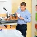 Man printing on coffee mugs in workshop