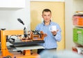 Man printing on coffee mugs in workshop