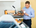 Man printing on coffee mugs in workshop