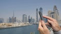 A man prints a message on the phone in the background of the panorama of Dubai. Hand close-up.