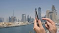 A man prints a message on the phone in the background of the panorama of Dubai. Hand close-up.