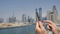 A man prints a message on the phone in the background of the panorama of Dubai. Hand close-up.