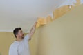 Man hand tear off old light wallpaper from wall preparing for home repair work removing wallpaper with a spatula Royalty Free Stock Photo